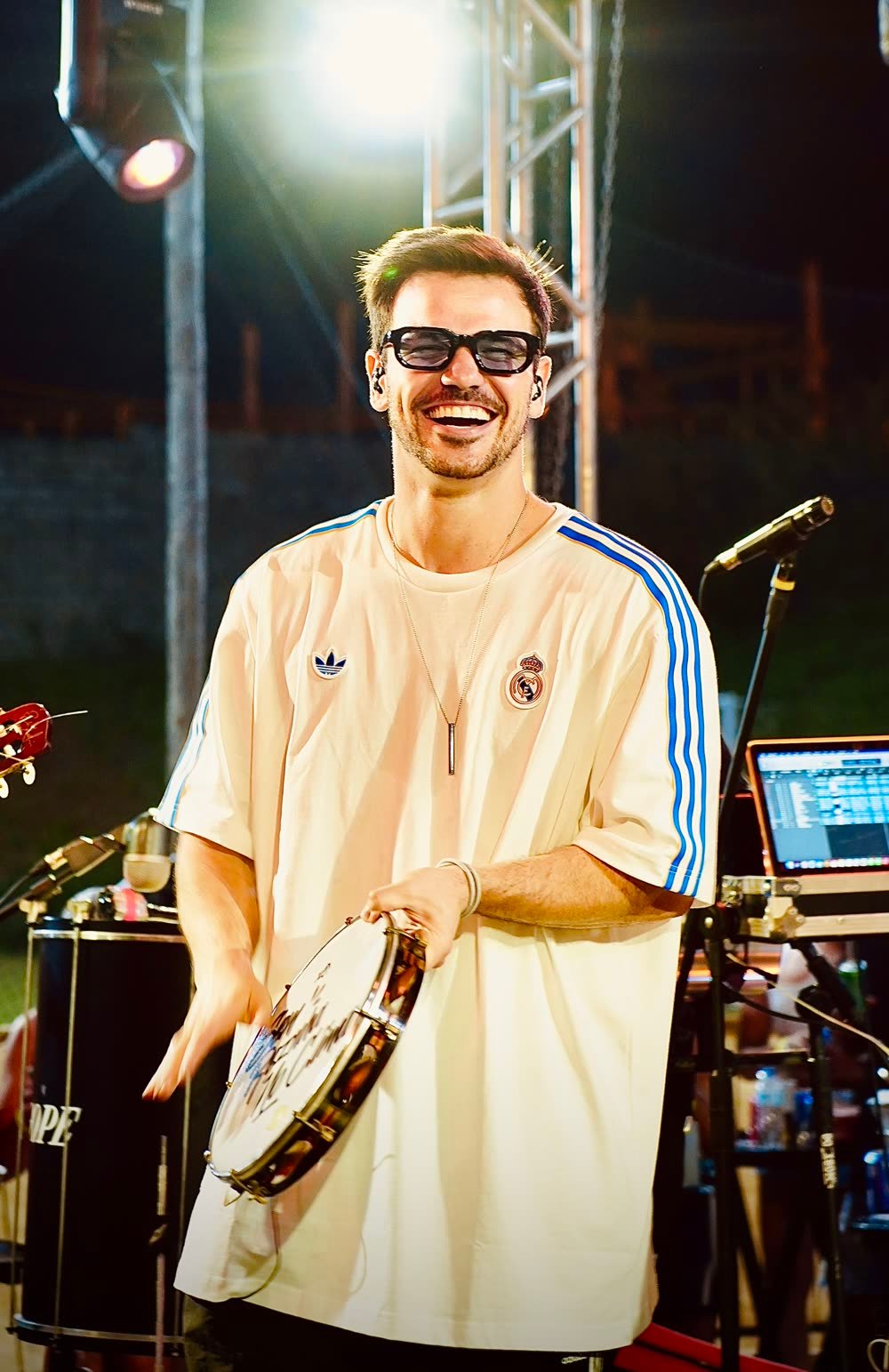 Rafa Grego sorrindo com o pandeiro na mao, no palco